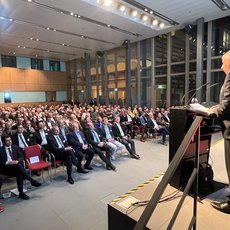 Hans Stöcker am Rednerpult mit Blick auf den vollbesetzten Vortragssaal