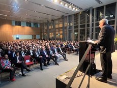 Hans Stöcker am Rednerpult mit Blick auf den vollbesetzten Vortragssaal