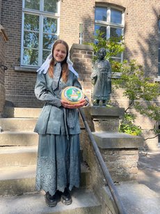 Isabell Schulte-Spechtel als Käsepionierin vor Statue von Maria Reymer