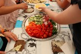 Kinder schmieren ihre Brote mit Gemüse, Obst und Käse