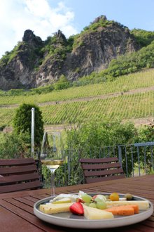 Käseteller und 1 Glas Wein vor der Kulisse des Weinbergs