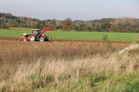 gepflügtes Feld mit rotem Traktor