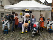 NRW-Milchmaskottchen Lotte mit den Milchbotschafterinnen der Landfrauen Cornelia Langreck und Marita Horstmann (v.l.) und Besuchern des Sendenhorster Wochenmarkts. 