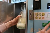 Kunde füllt Milch in einem Milchautomaten ab