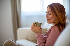 Frau auf dem Sofa mit einem Becher in der Hand