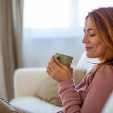 Frau auf dem Sofa mit einem Becher in der Hand