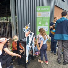 Kinder beim Melken am Kuhmodell