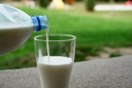 Milch wird aus einer Flasche in ein Glas geschüttet