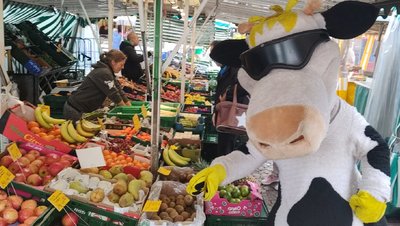 Marktstand mit Gemüse und Obst und Milchmaskottchen Kuh Lotte